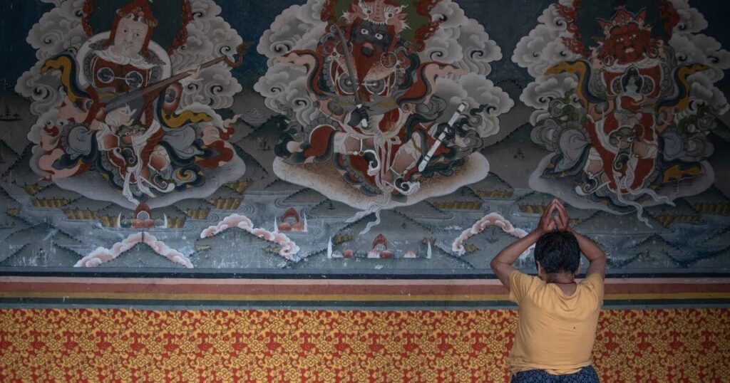 不丹寺廟壁畫前朝聖者祈禱